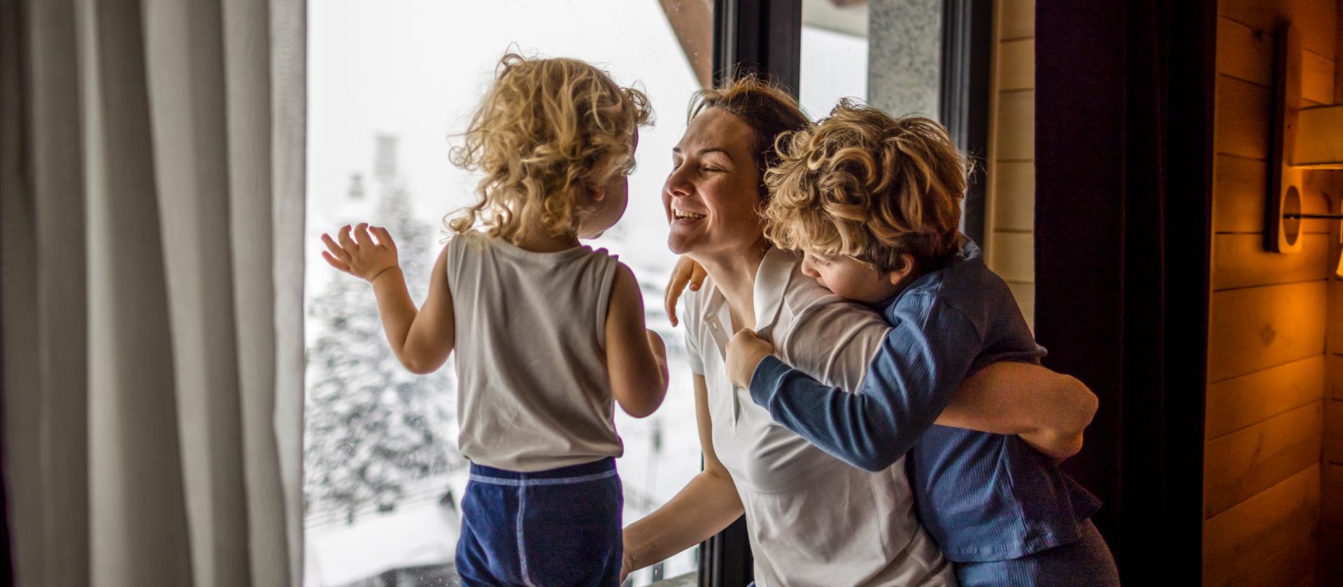 Glückliche Familie schaut im Winter aus dem Fenster 