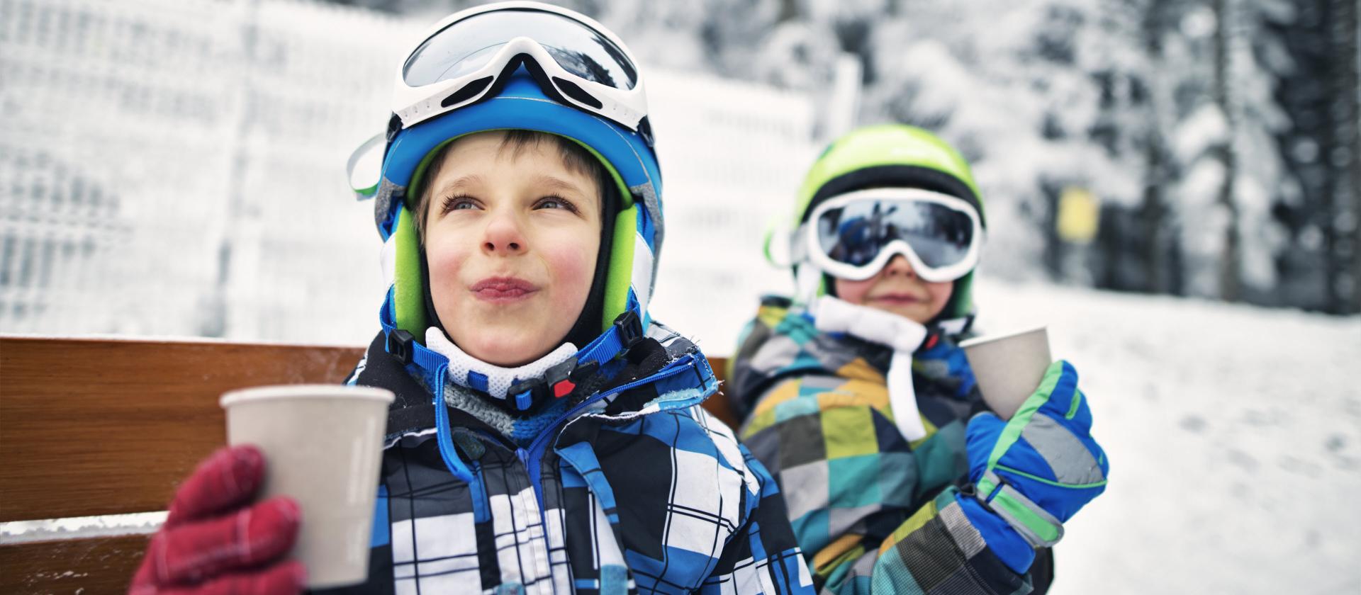 Garçons heureux qui font une pause ski et boivent un thé chaud.