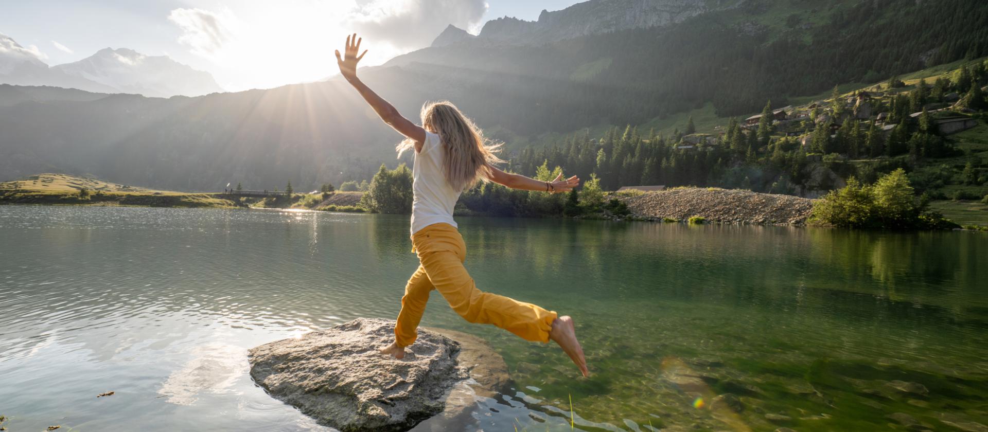 Frau-springt-auf-einen-felsen-in-einem-see