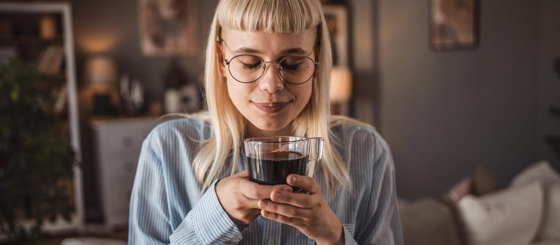 Junge Frau, die zu Hause einen schwarzen Kaffee geniesst