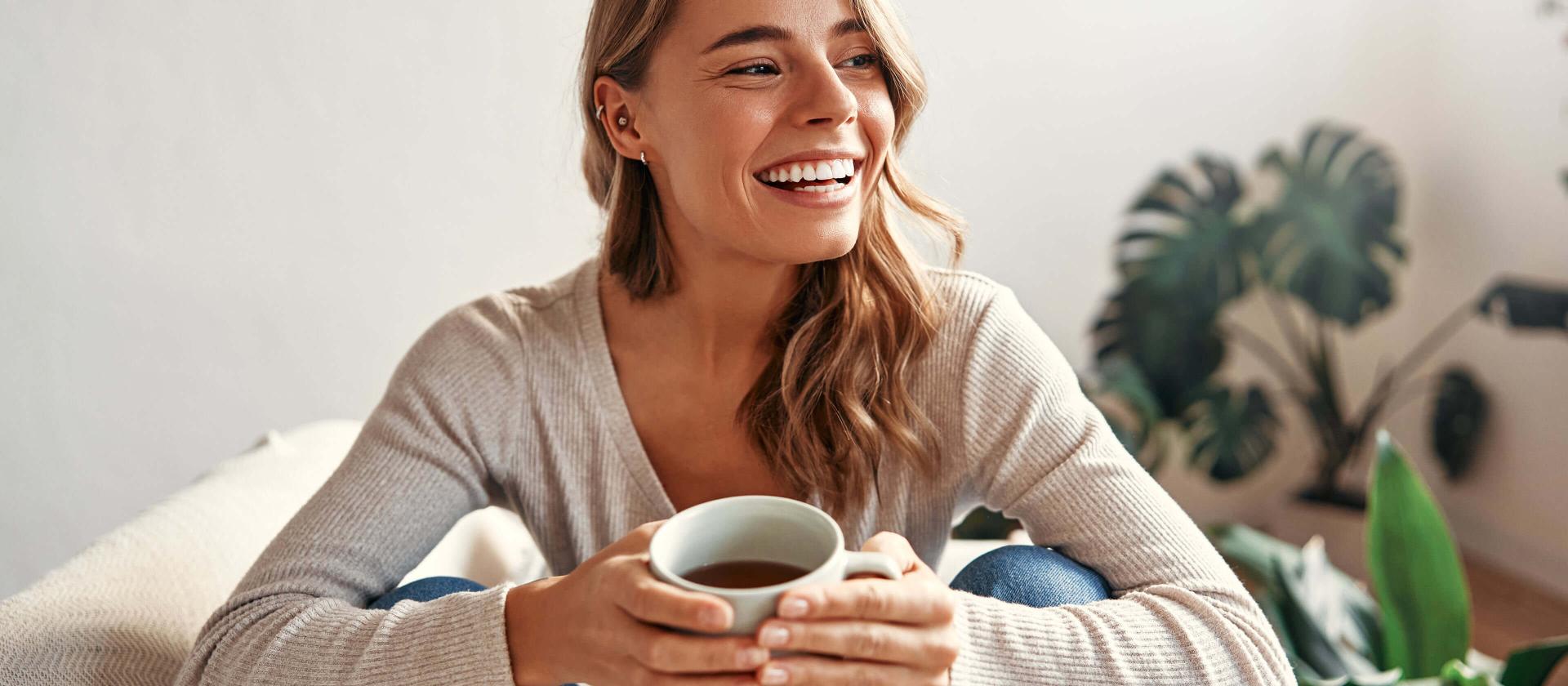 Junge Frau, die zuhause entspannt eine Tasse Kaffee geniesst.