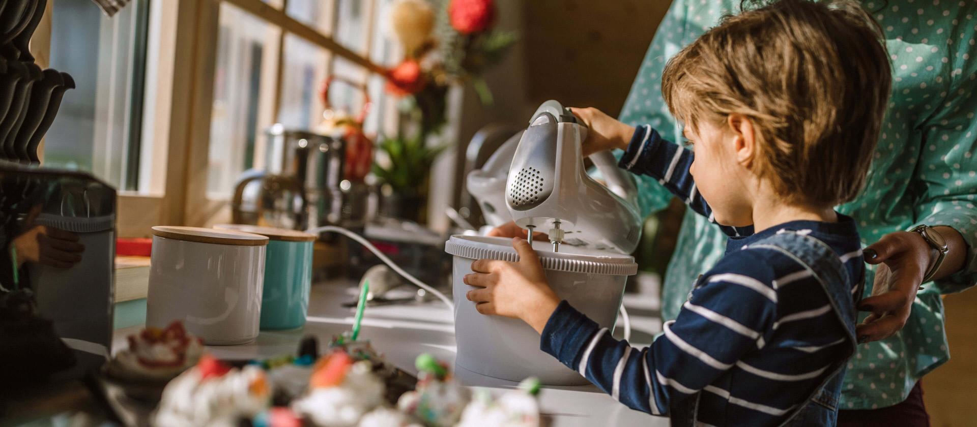 Junge hilft seiner Mutter beim Schlagen von Sahne