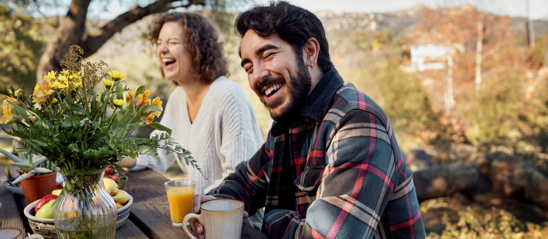 Couple souriant et riant à une table en bois en extérieur 