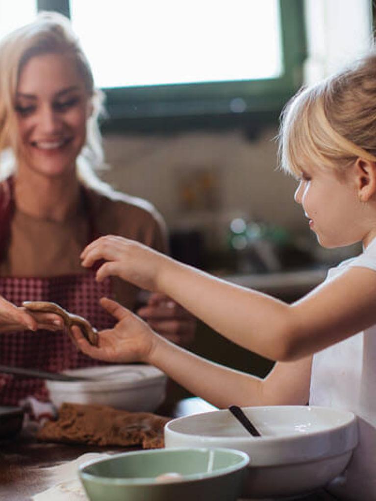 Mama und Tochter backen Weihnachtsgebäck in heller Küche.