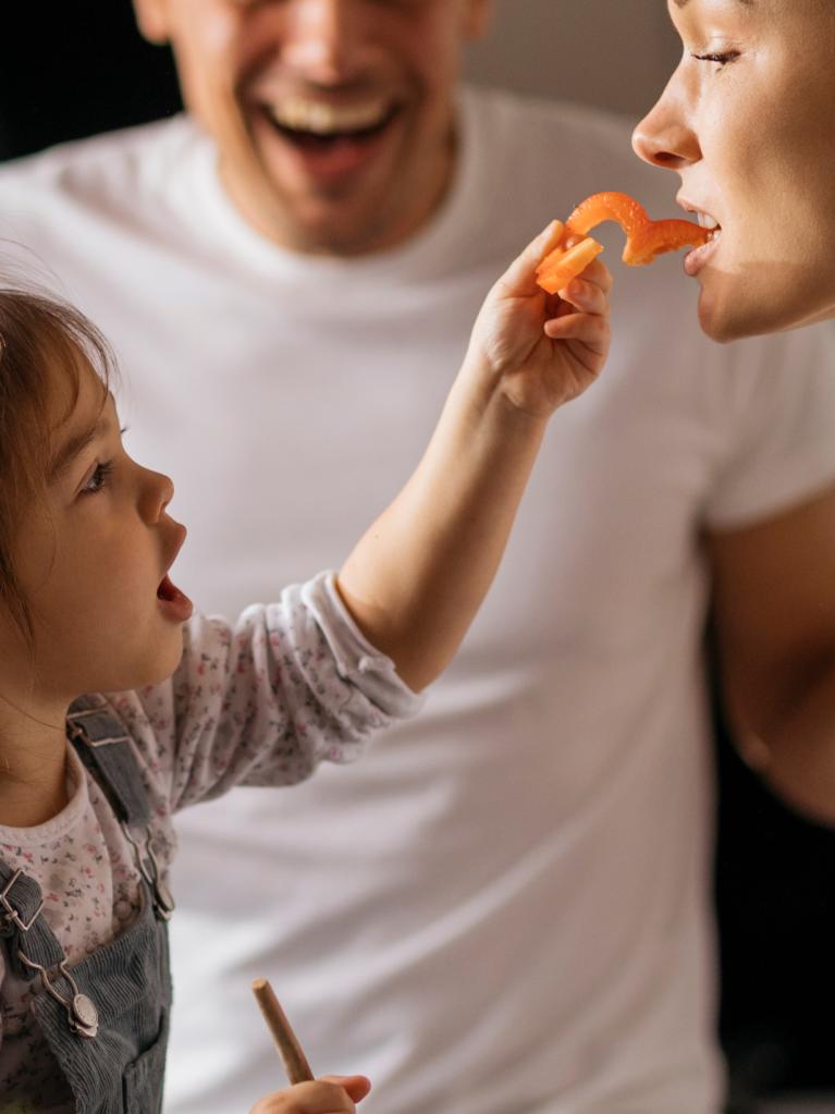 Kind füttert ihre Mama mit einer Paprika