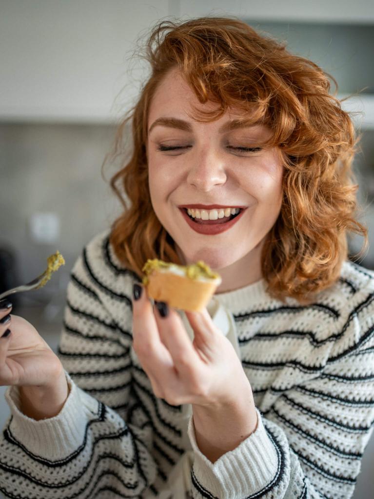 Junge Frau geniesst eine selbstgemachte Speise in der Küche