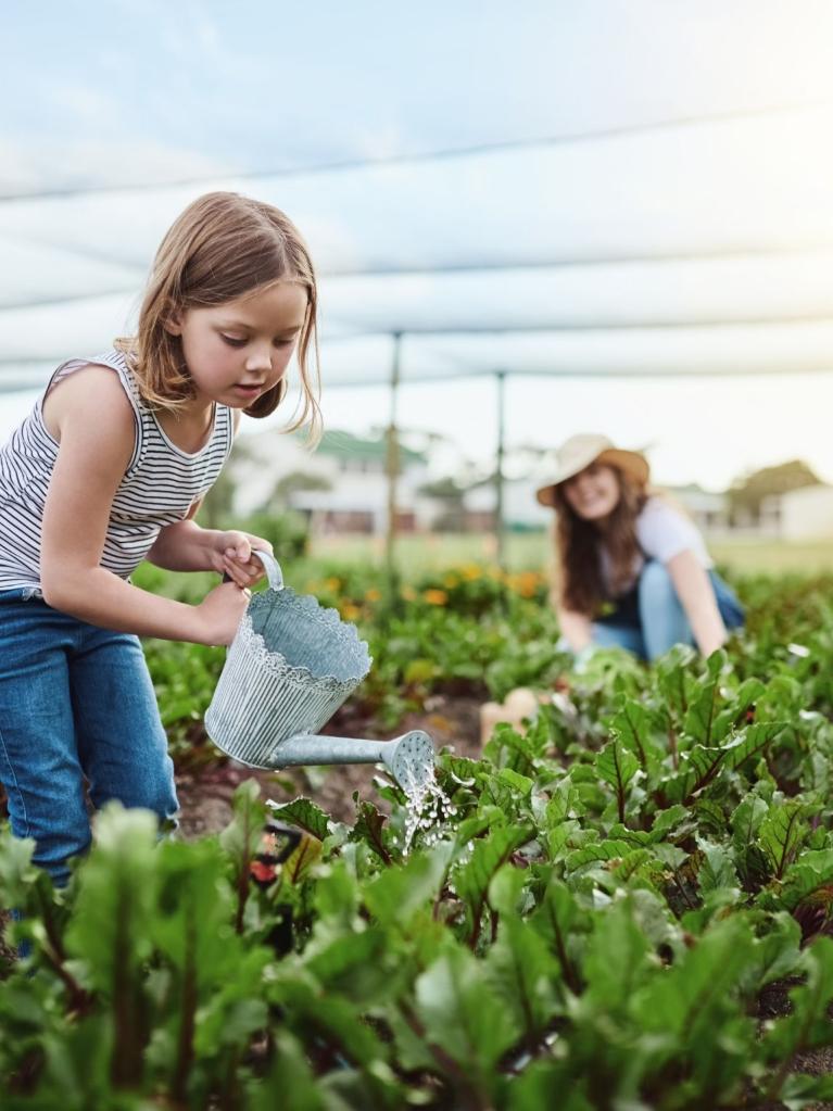 Mädchen, das im Garten Pflanzen giesst
