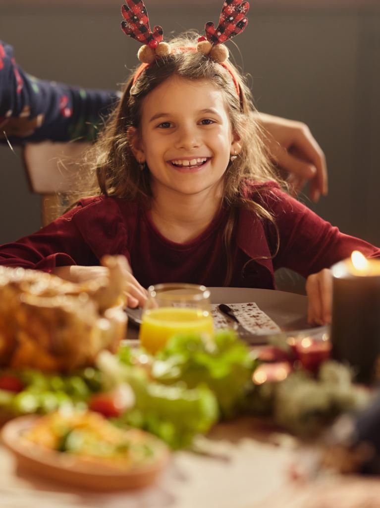 Festlich gekleidetes Mädchen am Esstisch mit Familie 
