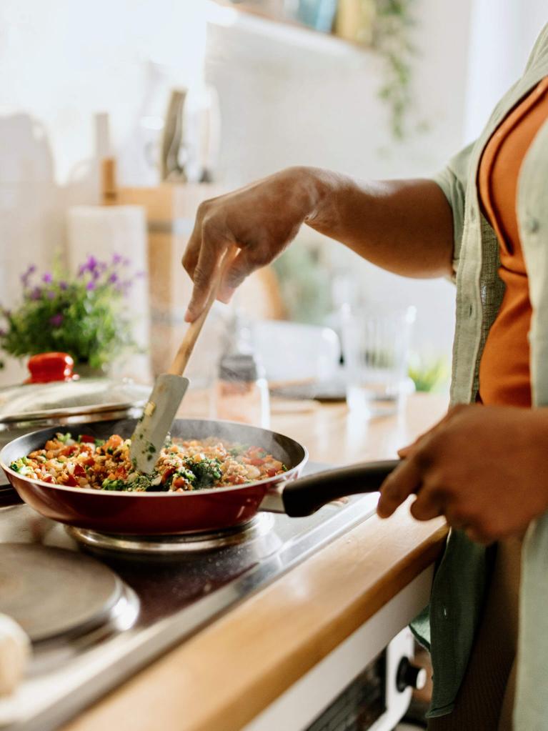 Femme préparant un mélange de légumes et de quinoa dans une poêle