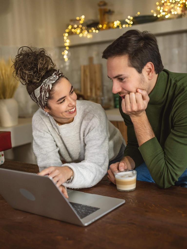 Junges Paar informiert sich auf dem Laptop während der Weihnachtszeit
