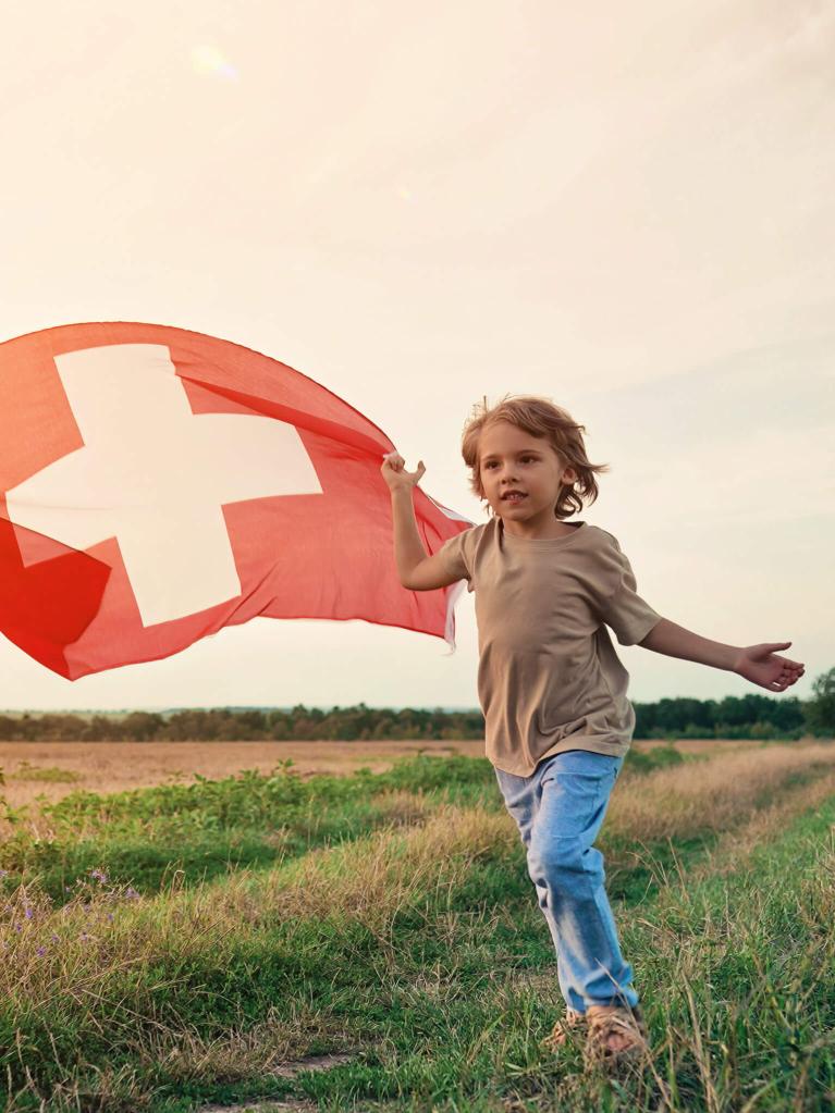 Deux garçons qui courent en portant un drapeau suisse pour la fête nationale du 1er août