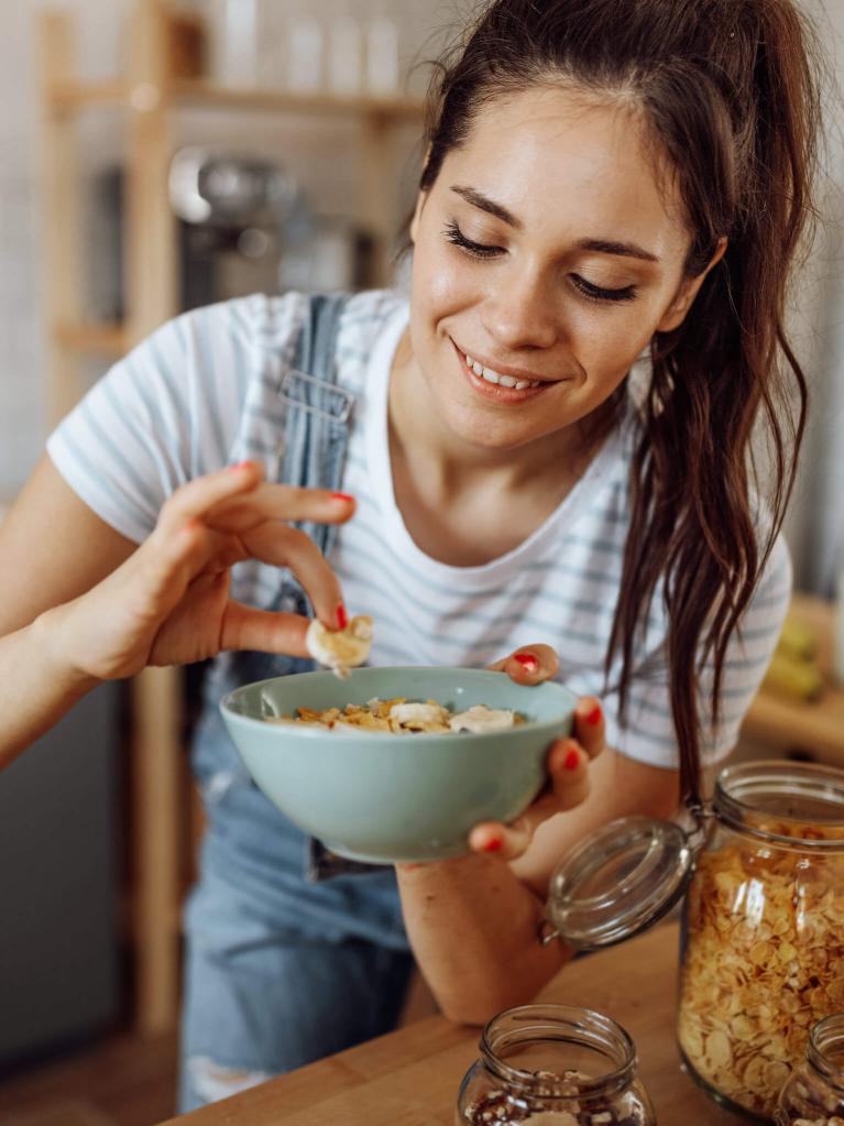 Jeune femme goûtant le petit-déjeuner qu'elle vient de préparer