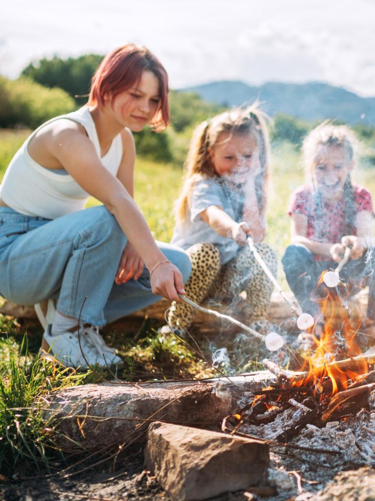Geschwister grillen an einem Lagerfeuer