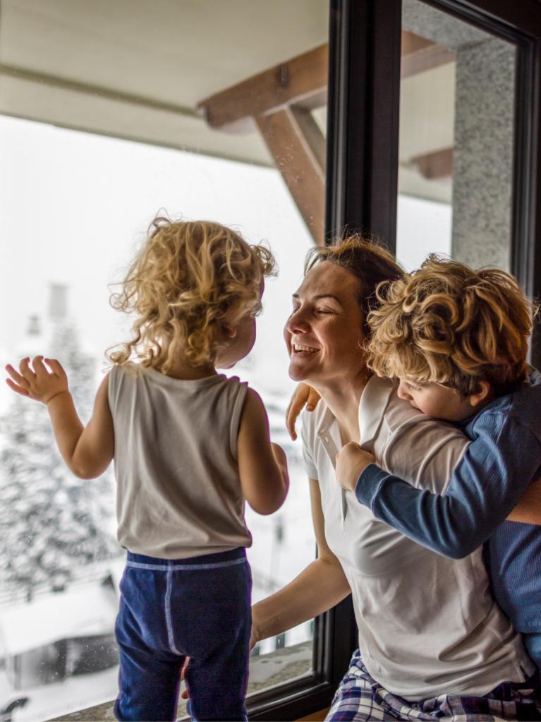Glückliche Familie schaut im Winter aus dem Fenster 