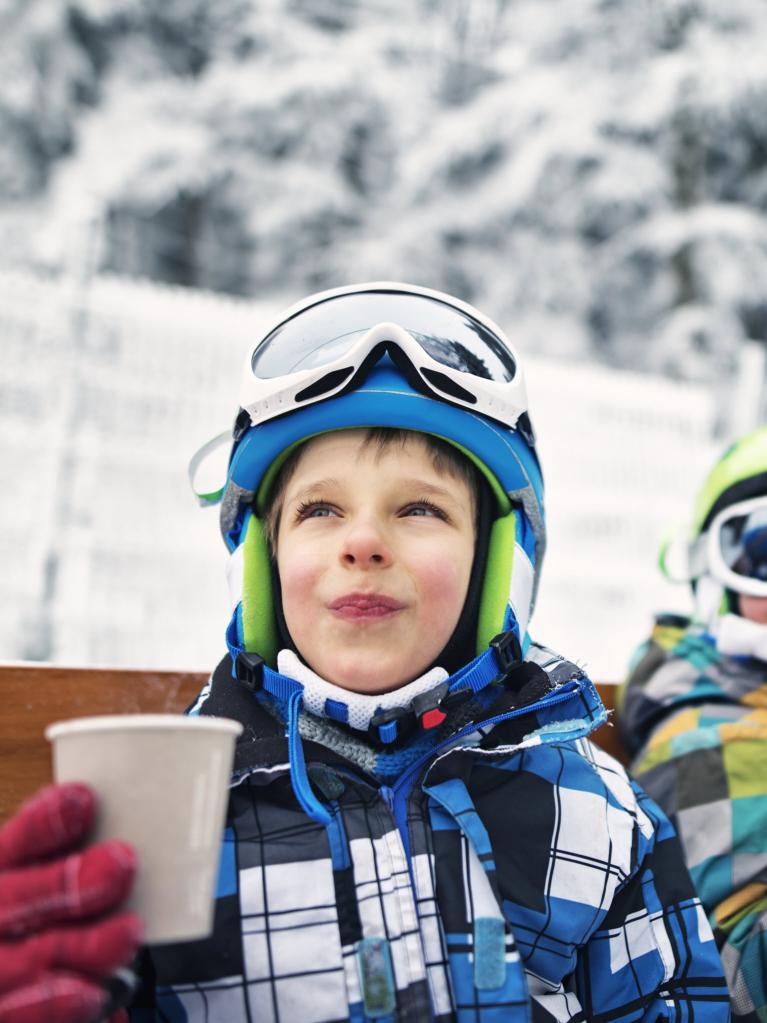 Garçons heureux qui font une pause ski et boivent un thé chaud.