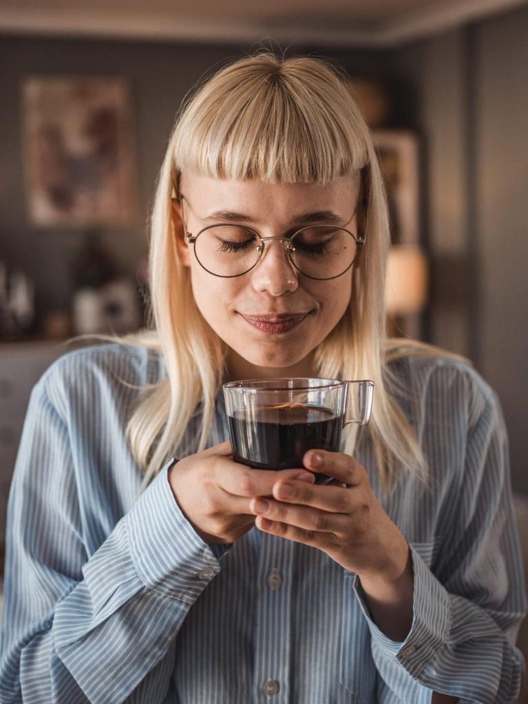 Junge Frau, die zu Hause einen schwarzen Kaffee geniesst 