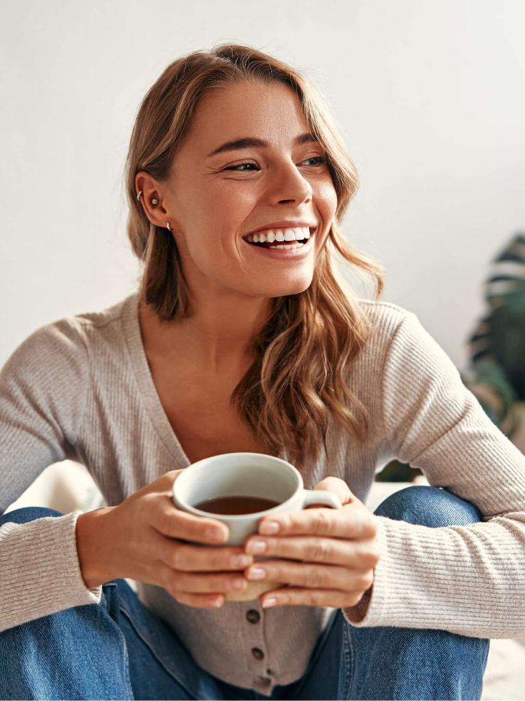 Junge Frau, die zuhause entspannt eine Tasse Kaffee geniesst.