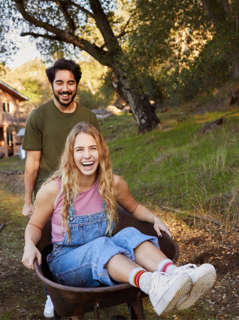 Fille-qui-se-fait-pousser-sur-une-brouette-par-un-ami-en-riant