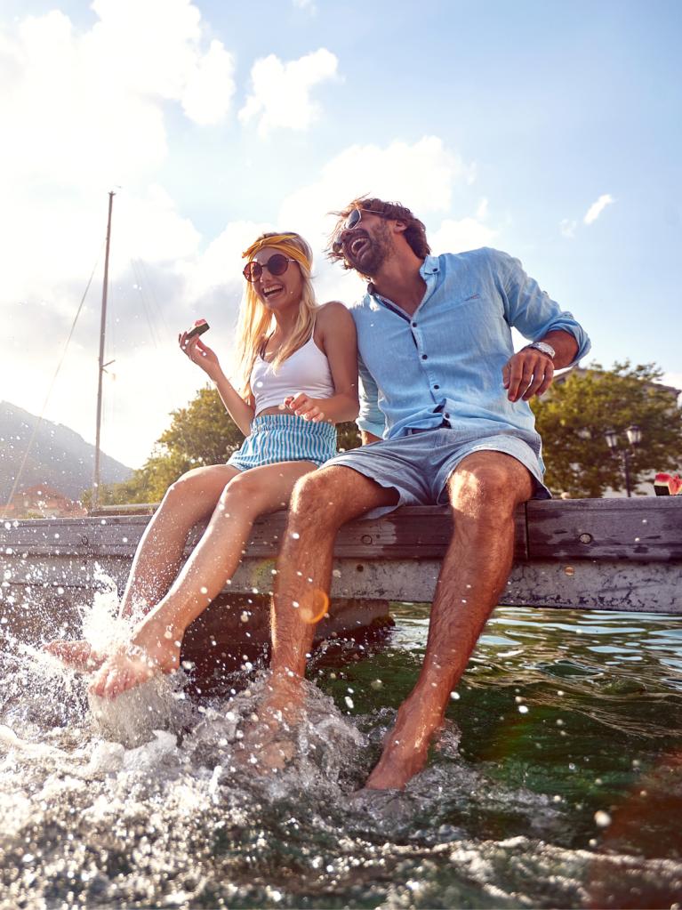 Lachendes Paar sitzt am Wasser 