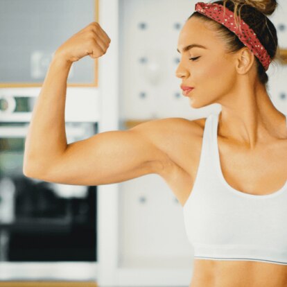 Header_Protein_Fau_1070x535 (1).png Frau zeigt stolz ihre Armmuskeln in der Küche