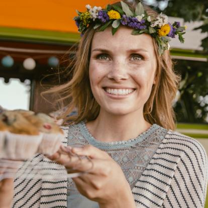 Header_no_typical_vegan_1070x535_210703.jpg Frau mit einem Muffin Blech und Blumen im Haar