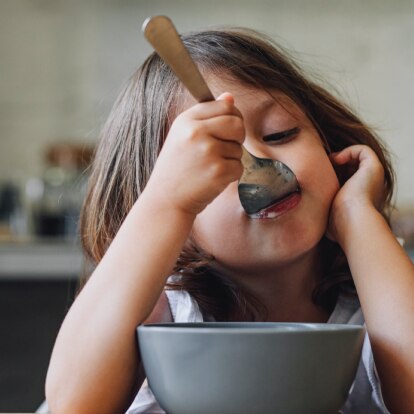 Header.png Mädchen isst gelangweilt am Tisch