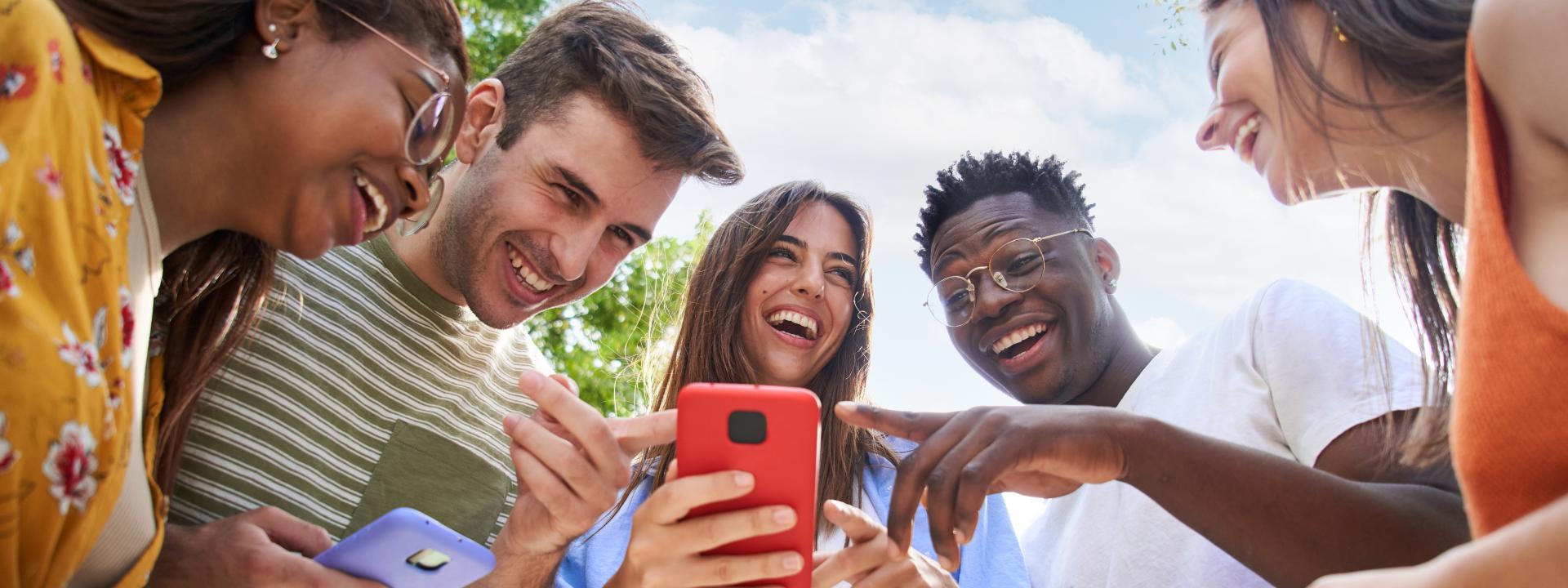 Groupe de jeunes rient en lisant quelque chose sur un smartphone.