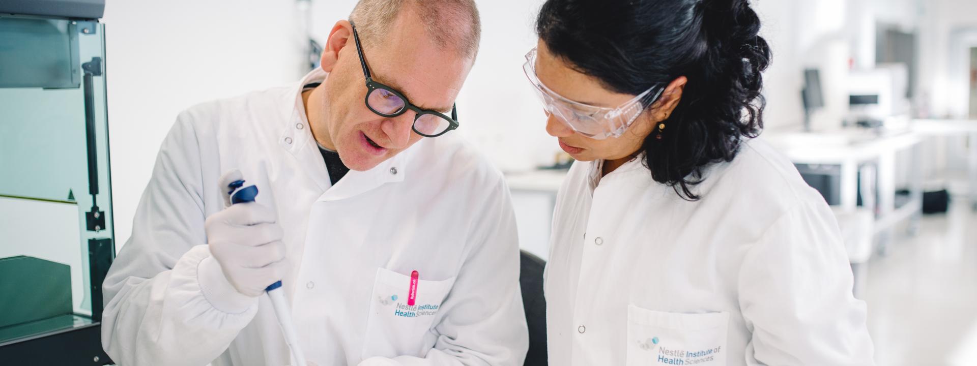 Ein Mann und eine Frau in weissen Laborkitteln testen eine Substanz in einem Nestlé-Labor.