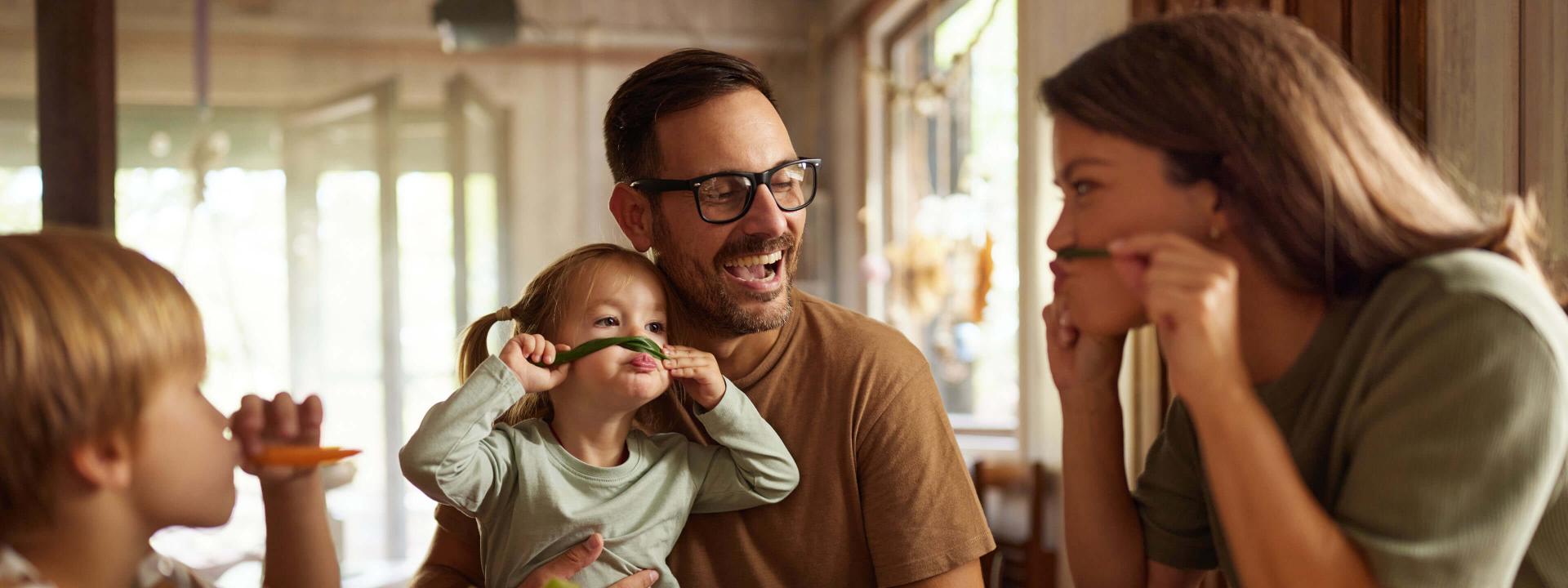 Fröhliche Familie geniesst gemeinsam ein Essen am Tisch und hat dabei richtig Spass.