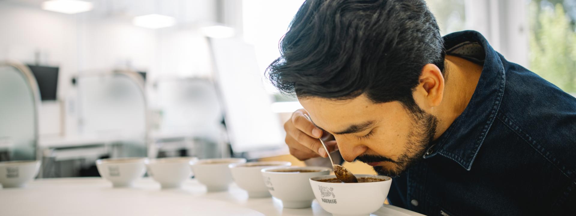 Ein Mann riecht an verschiedenen Sorten gemahlenen Kaffees im Nestlé-Forschungszentrum.