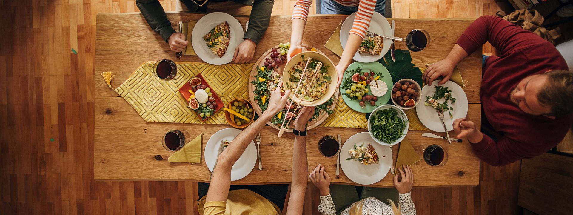 Gruppe von Freunden sitzt am Tisch und genießt gemeinsam ein Essen