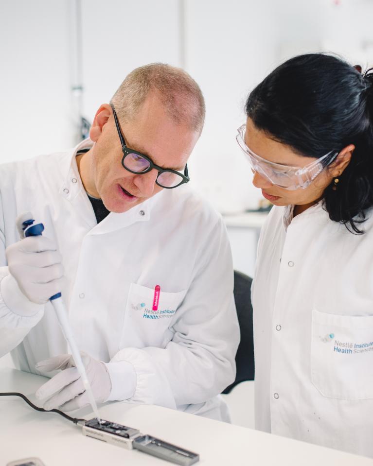 Un homme et une femme en blouse blanche testent une substance dans un laboratoire Nestlé.