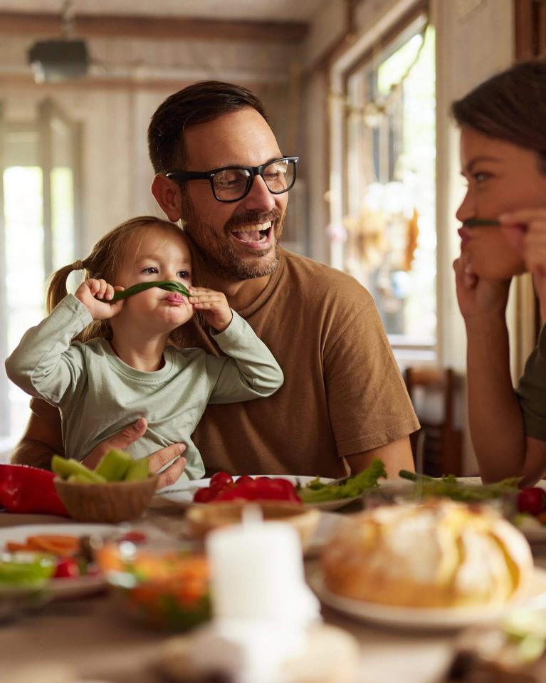 Fröhliche Familie geniesst gemeinsam ein Essen am Tisch und hat dabei richtig Spass