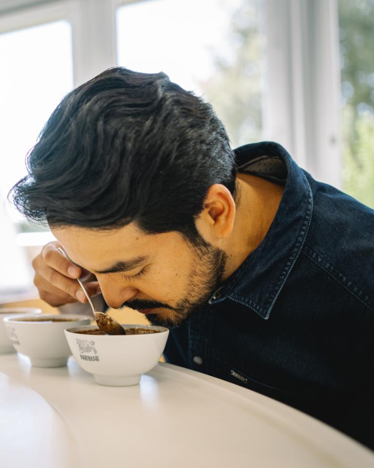Un homme sent différentes variétés de café moulu au centre de recherche Nestlé.