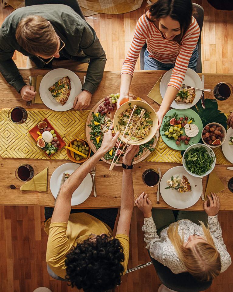 Gruppe von Freunden sitzt am Tisch und genießt gemeinsam ein Essen