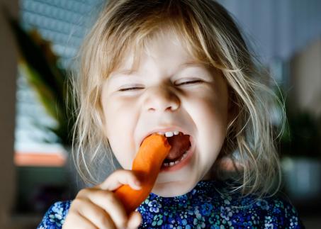 Kind isst eine Karotte