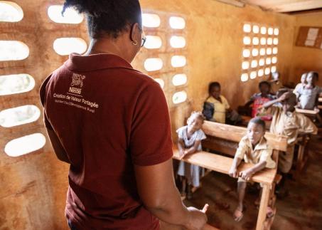 Eine Frau spricht mit einer Gruppe von Kindern in einem Dorf