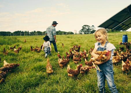 Jeune fille tenant une poule dans ses bras à l’extérieur