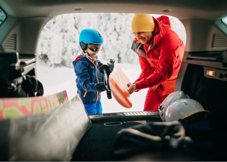 Familie bereitet Snowboard im Kofferaum vor