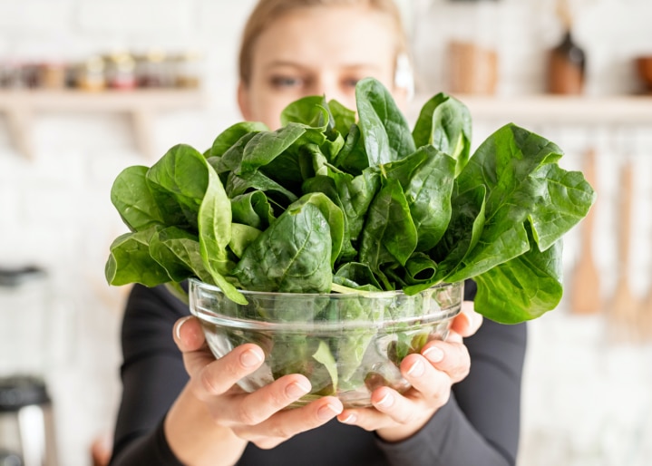 Frau mit Spinat in der Hand