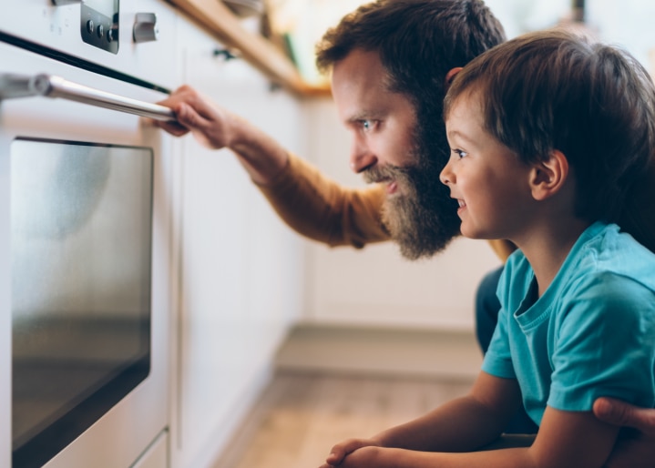Vater und Sohn schauen in den Backofen