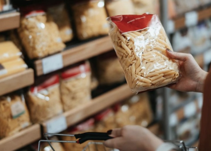Une femme tient un paquet de pâtes à la main