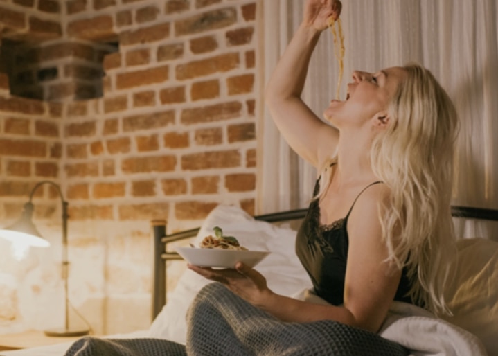 une femme mange des pâtes au lit