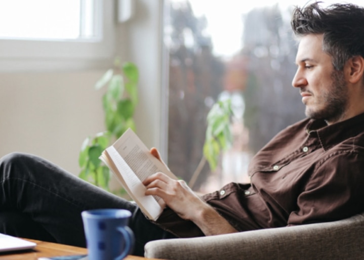 Un homme lit un livre dans son salon