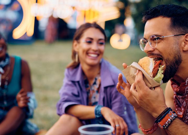 Freunde sitzen auf einem Festival zusammen und essen Burger