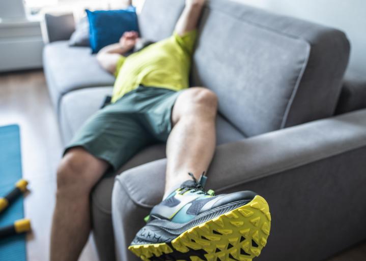 Mann liegt nach Sport auf dem Sofa