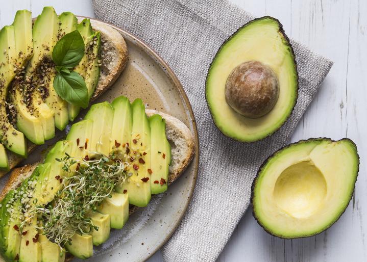 Deux tartines d'avocat coupé en tranches et un avocat coupé en deux