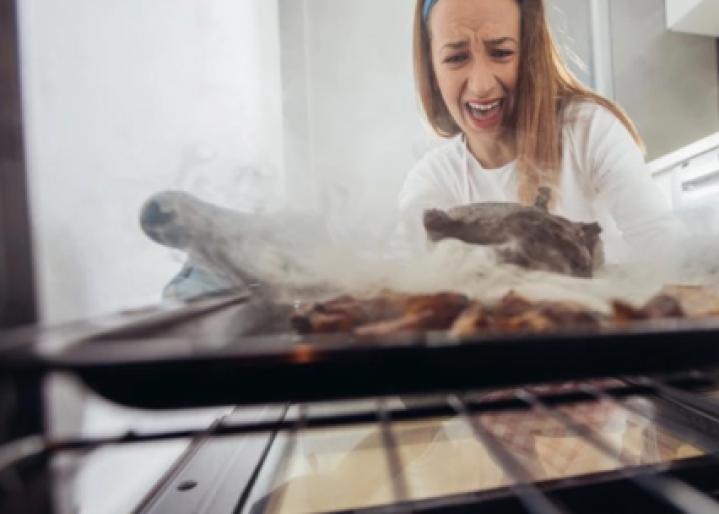 Frau schaut in Ofen wo verbranntest Essen drin ist
