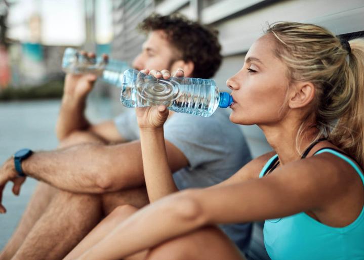 Zwei Personen, die Wasser trinken, in Sportkleidung