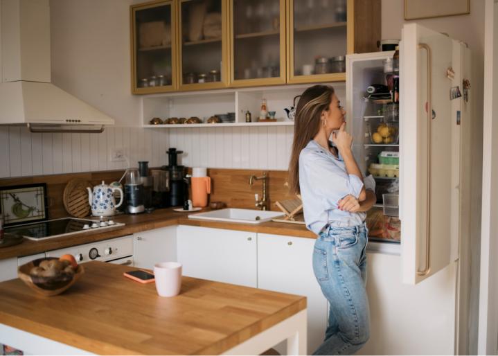 Frau steht nachdenklich vor dem Kühlschrank